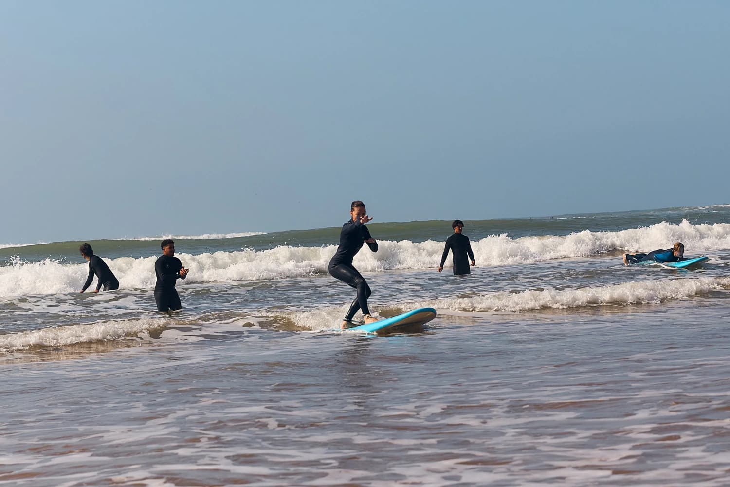 Beginner surfer standing on small wave at Aman Surf & Yoga in Imsouane, Morocco