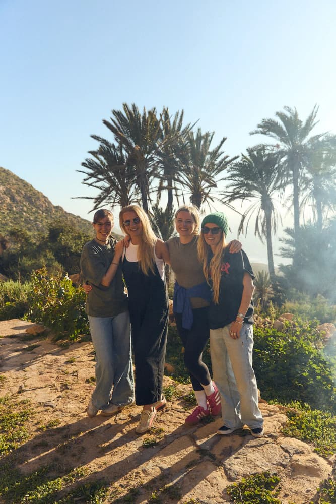 Friends among palms by ocean at Aman Surf & Yoga in Imsouane, Morocco