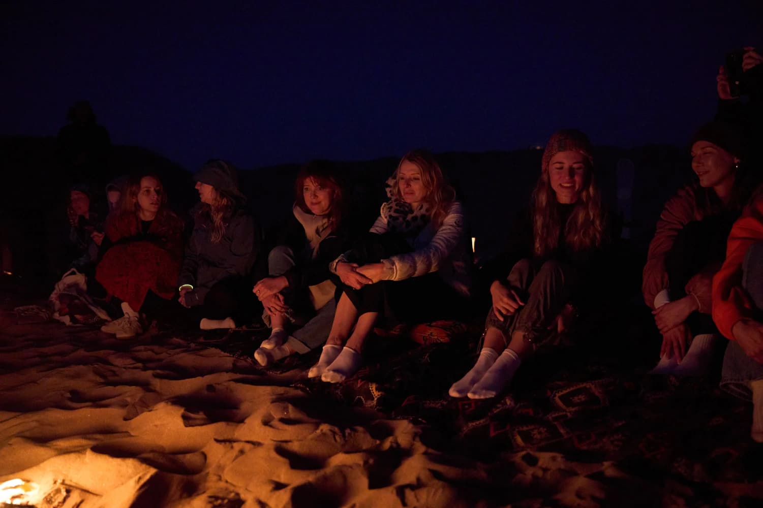 Friends around desert fire at night at Aman Surf & Yoga in Imsouane, Morocco