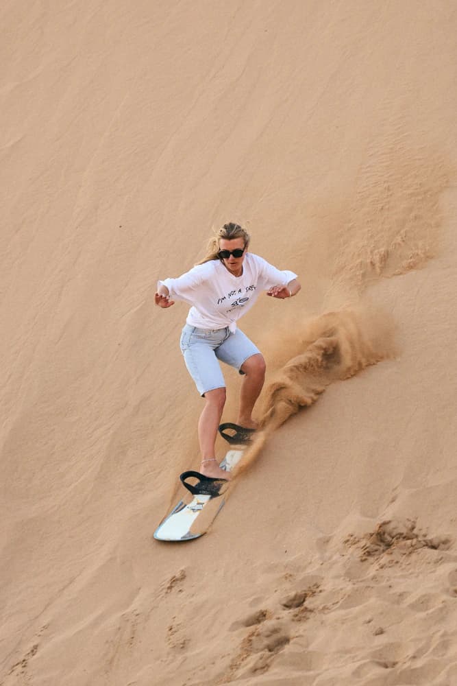 Solo sandboarding down dune at Aman Surf & Yoga in Imsouane, Morocco