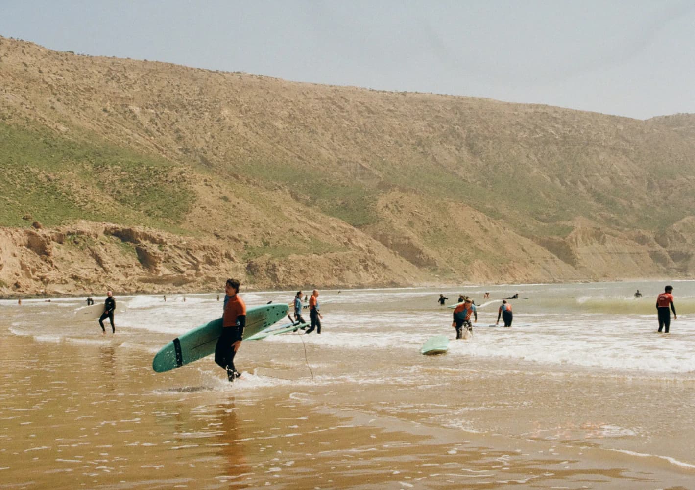 Surfers carrying boards to ocean at Aman Surf & Yoga in Imsouane, Morocco