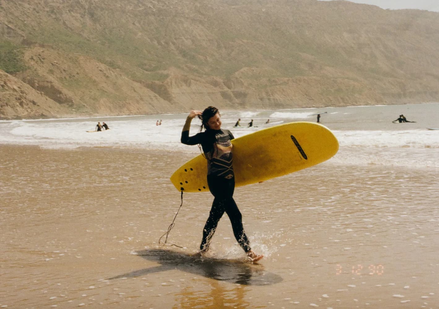 Woman yellow surfboard beach walk at Aman Surf & Yoga in Imsouane, Morocco