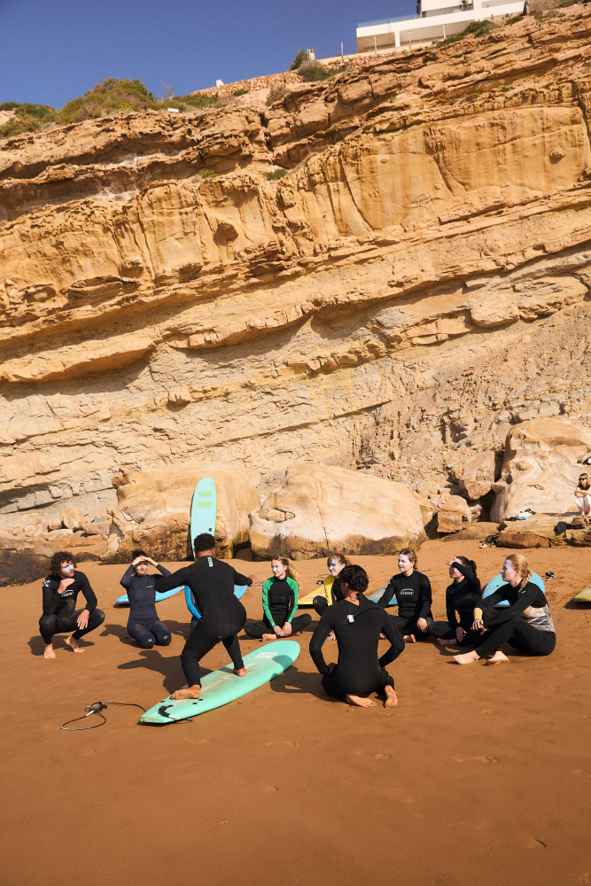 Surf coach leading a beach instruction circle in Imsouane